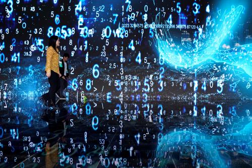 FILE PHOTO: People walks in front of a screen at the World Internet Conference (WIC) in Wuzhen, Zhejiang province, China, October 20, 2019. REUTERS/Aly Song/File Photo