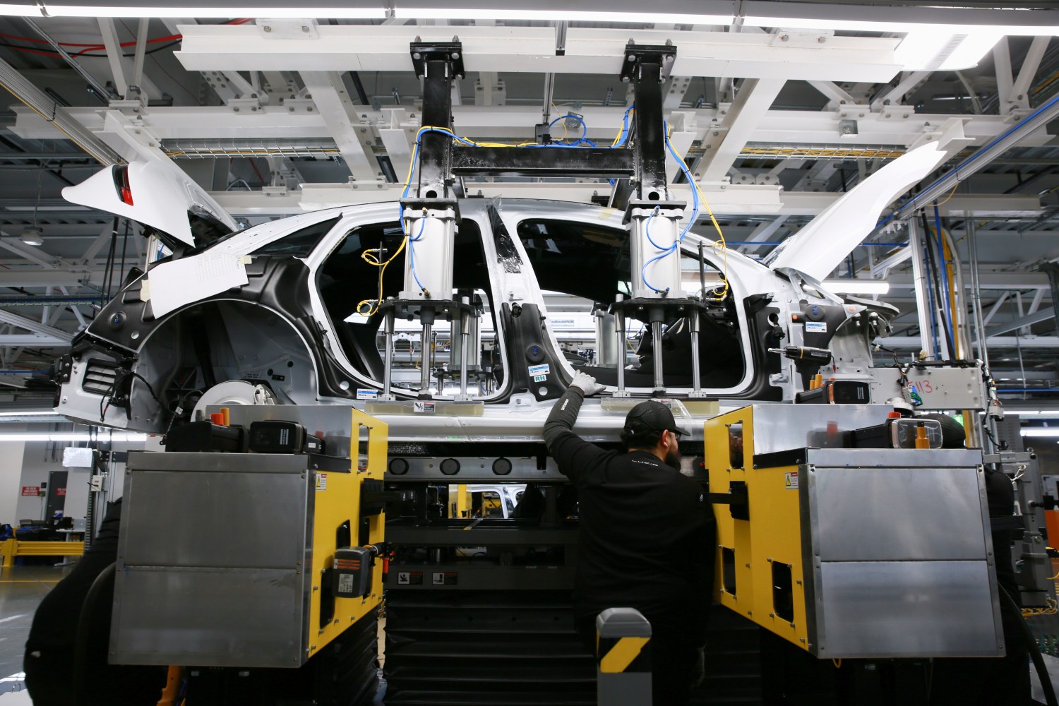 Workers marry the body structure with the battery pack and the front and rear sub frames as they assemble electric vehicles at the Lucid Motors plant in Casa Grande, Arizona, U.S.