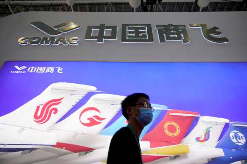A man walks past the logo of Commercial Aircraft Corporation of China (COMAC) at the China International Aviation and Aerospace Exhibition, or Airshow China, in Zhuhai, Guangdong province, China September 29, 2021. REUTERS/Aly Song