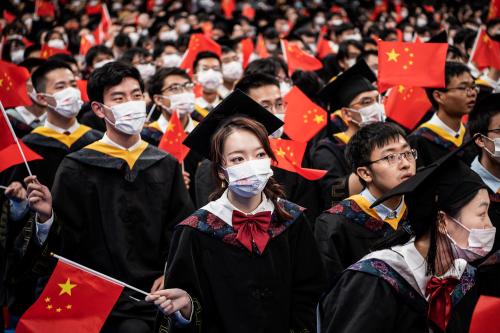 Chinese students from Huazhong University of Science and Technology wave flags during the graduation ceremony in the school's gym.