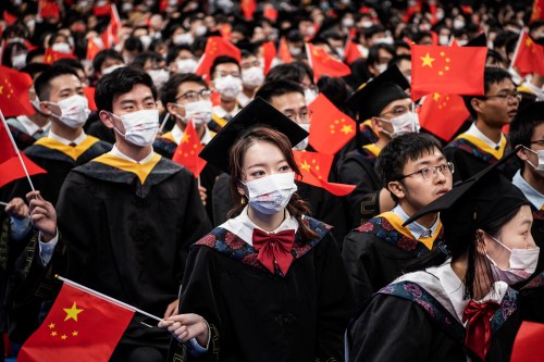 Chinese students from Huazhong University of Science and Technology wave flags during the graduation ceremony in the school's gym.