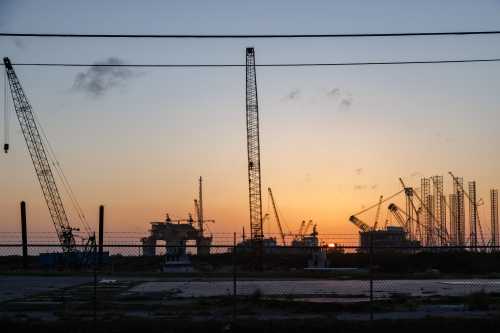 The sun sets beyond machinery at a Kiewit Offshore Services construction site in Ingleside, Texas on July 18, 2022. Kiewit is manufacturing an offshore oil drilling platform called 'Vito' for the Shell company, which, upon completion, will be installed in the Gulf of Mexico to extract petroleum for gasoline resources. (Photo by Bryan Olin Dozier/NurPhoto)NO USE FRANCE