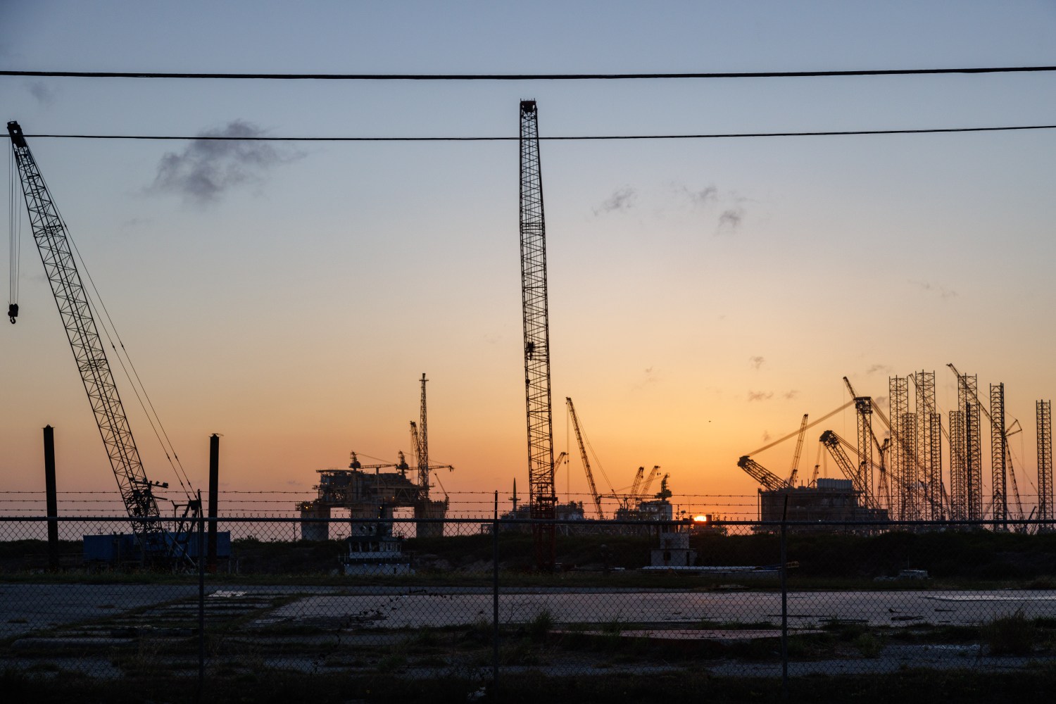 The sun sets beyond machinery at a Kiewit Offshore Services construction site in Ingleside, Texas on July 18, 2022. Kiewit is manufacturing an offshore oil drilling platform called 'Vito' for the Shell company, which, upon completion, will be installed in the Gulf of Mexico to extract petroleum for gasoline resources. (Photo by Bryan Olin Dozier/NurPhoto)NO USE FRANCE
