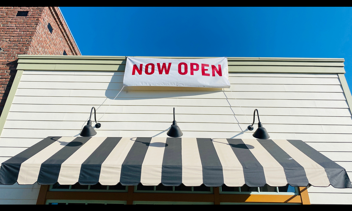 A "Now Open" sign hangs outside a business
