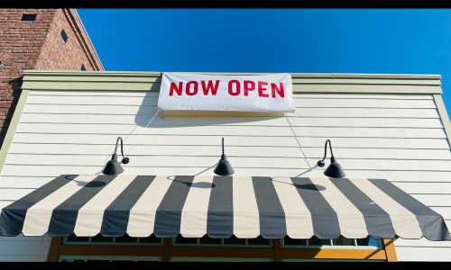 A "Now Open" sign hangs outside a business