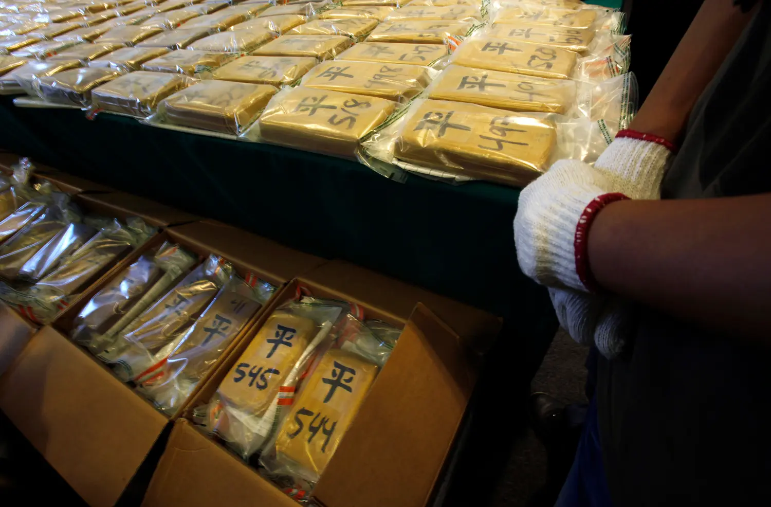 A customs officer stands beside a total of 649 kg (1,430 pounds) of cocaine during a news conference held by the Customs and Excise Department in Hong Kong July 6, 2012. Customs officers seized a record amount of cocaine with a street value of HK$760 million ($98 million), a government radio reported on Friday. The drugs were found in a container coming from Ecuador at the Kwai Chung Container Terminals and three men have been arrested so far.  REUTERS/Bobby Yip (CHINA - Tags: CRIME LAW DRUGS SOCIETY)