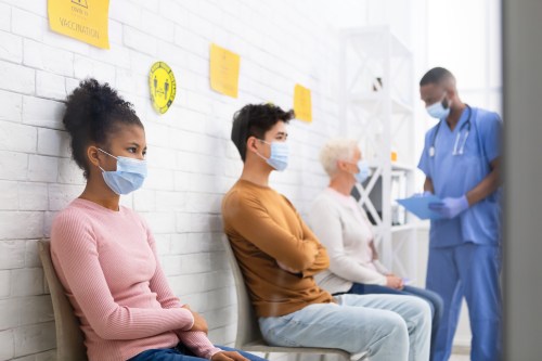 Diverse patients with face masks sitting in queue in hospital waiting room