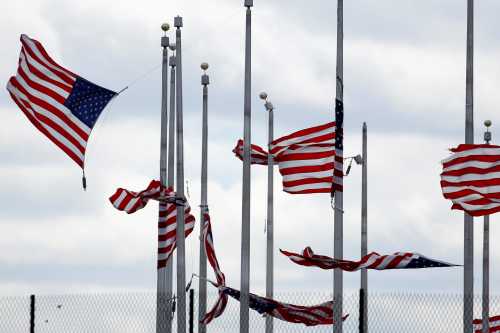 American flags partially torn from their poles fly as a storm producing strong winds passes through Washington, U.S., March 2, 2018.      REUTERS/Joshua Roberts