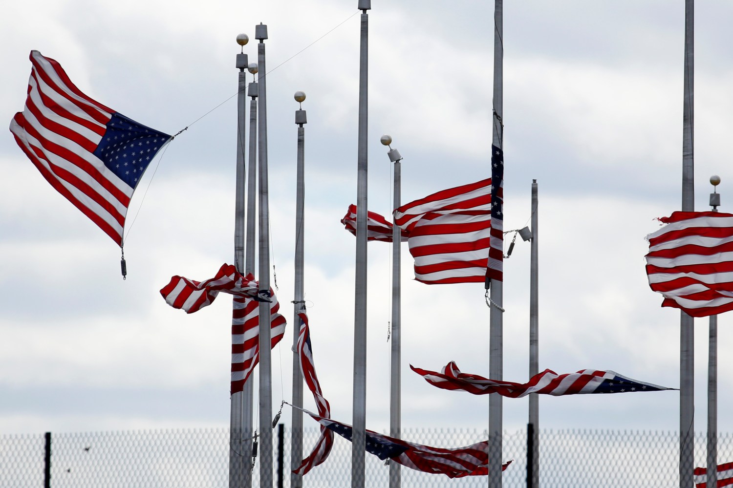 American flags partially torn from their poles fly as a storm producing strong winds passes through Washington, U.S., March 2, 2018.      REUTERS/Joshua Roberts