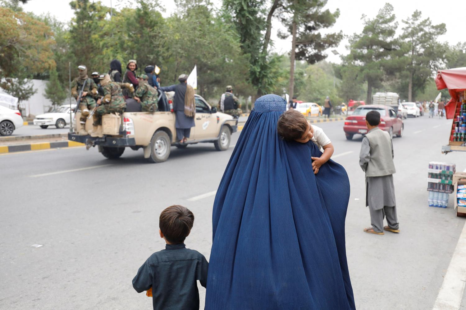 An Afghan woman walks with her children on the anniversary of the fall of Kabul on a street in Kabul, Afghanistan, August 15, 2022. REUTERS/Ali Khara