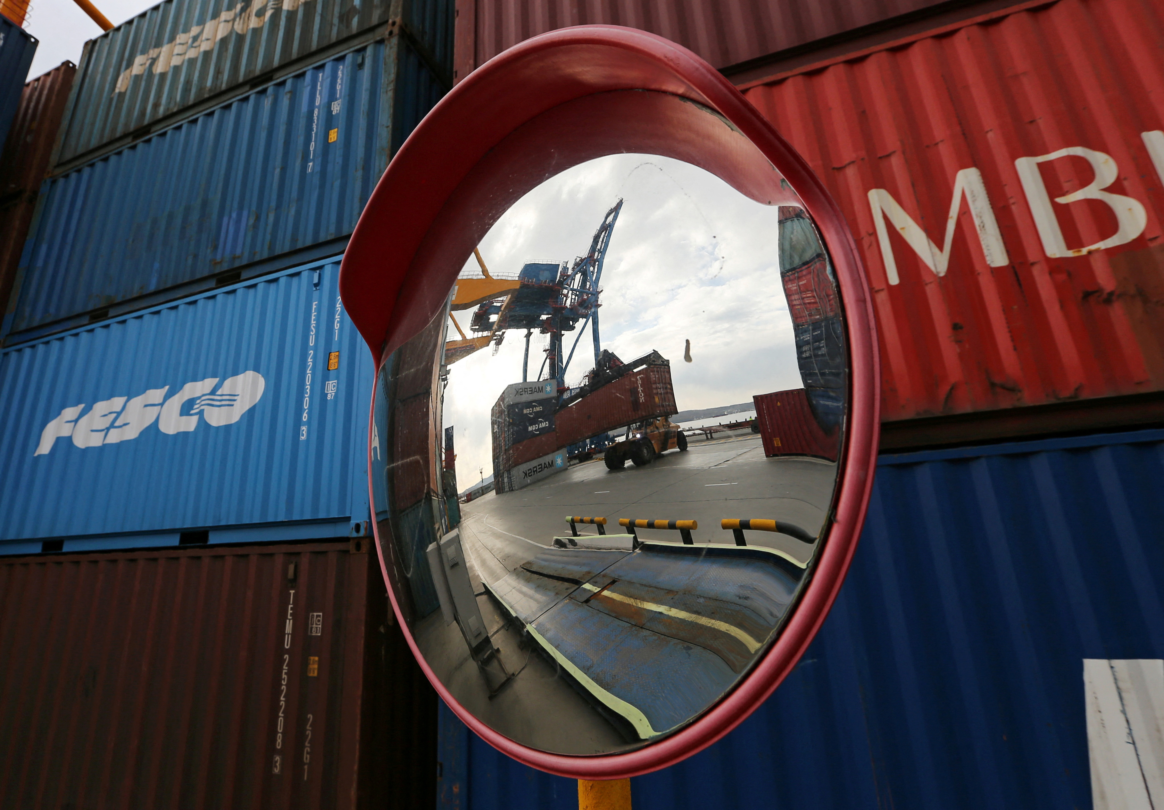 FILE PHOTO: A vehicle moving a shipping container is reflected in a mirror at a commercial port in Vladivostok, Russia October 22, 2021. REUTERS/Tatiana Meel/File Photo