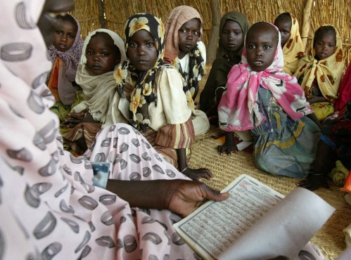 A Sudanese teacher reads to children at an Islamic school in the Abushock camp for displaced people in northern Darfur region of Sudan, August 16, 2004. The United Nations says 50,000 people have been killed and a million displaced since fighting broke out in Darfur between the Sudan government and two rebel groups in early 2003, sparking what has been called the world's worst humanitarian disaster. REUTERS/Antony Njuguna  AN/acm