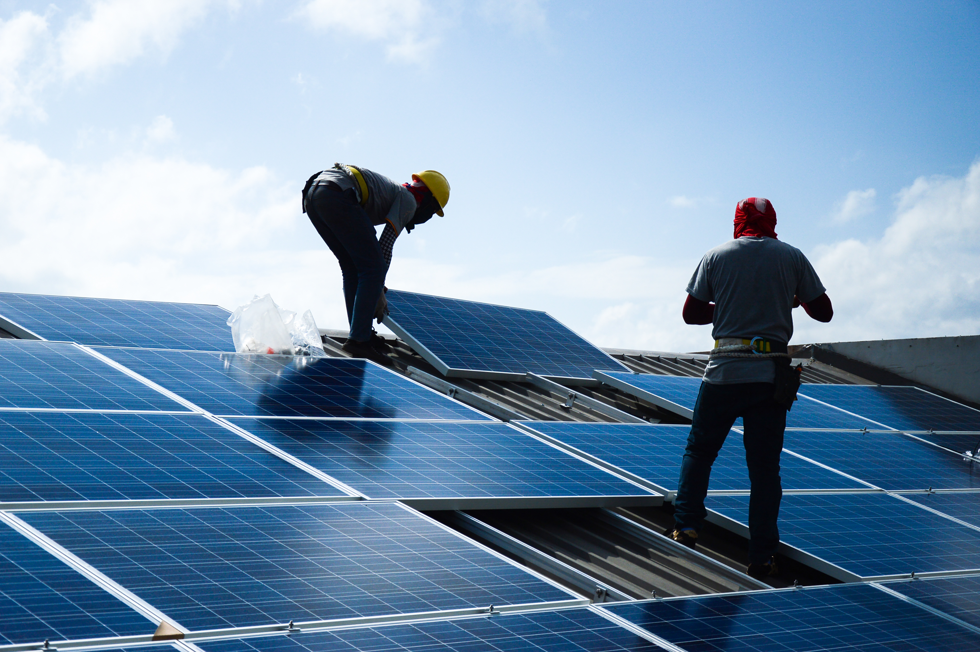 Two men installing solar panels on a roof