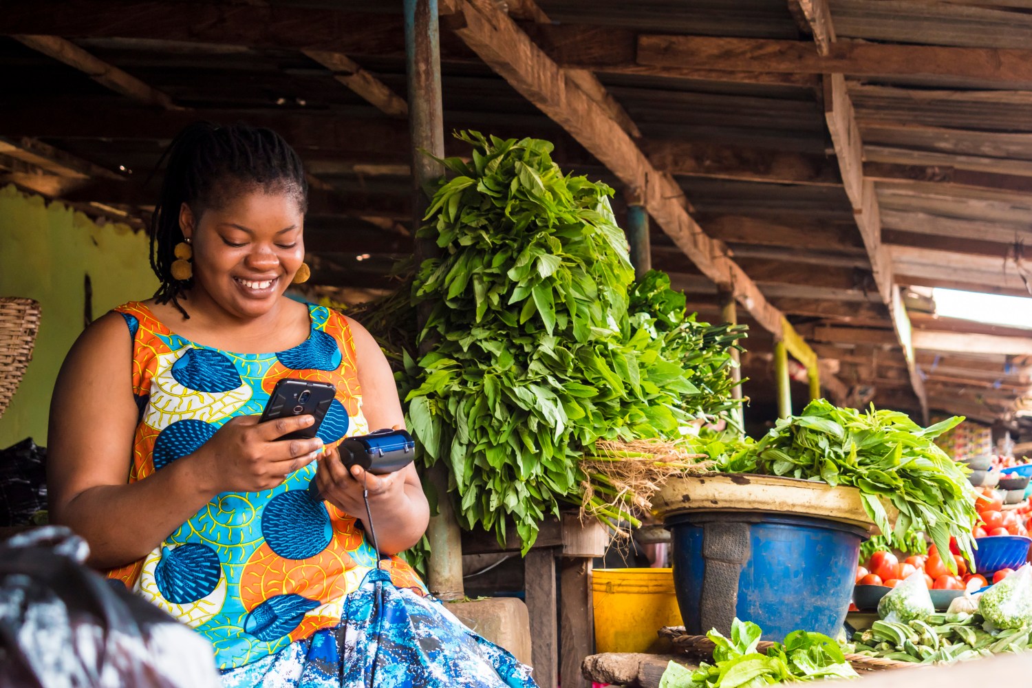 African,Woman,Using,Her,Phone,And,Also,Holding,A,Pos