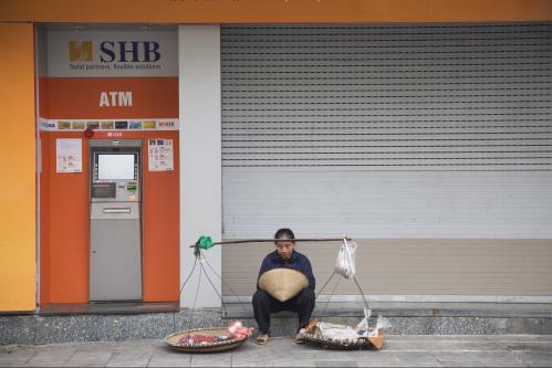 Vietnamese vendor sitting in front of SHB commercial bank branch