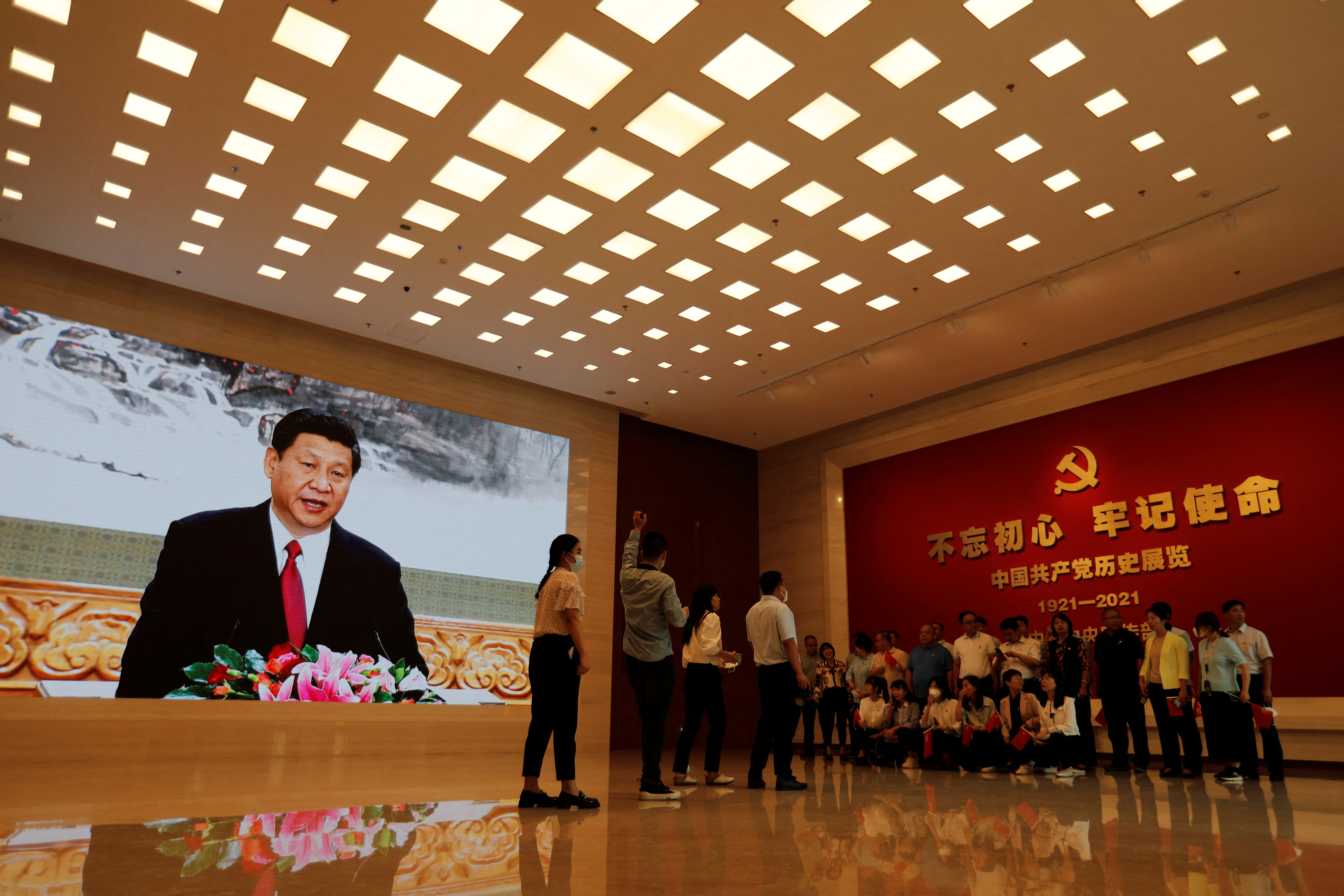 Visitors prepare for a group photo near a screen displaying an image of Chinese President Xi Jinping at the Museum of the Communist Party of China in Beijing, China September 3, 2022. REUTERS/Florence Lo