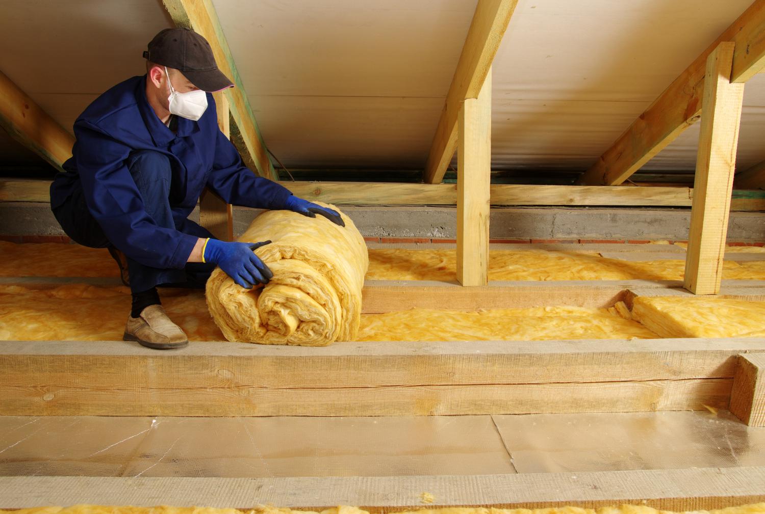 Man installing thermal insulation layer under the roof