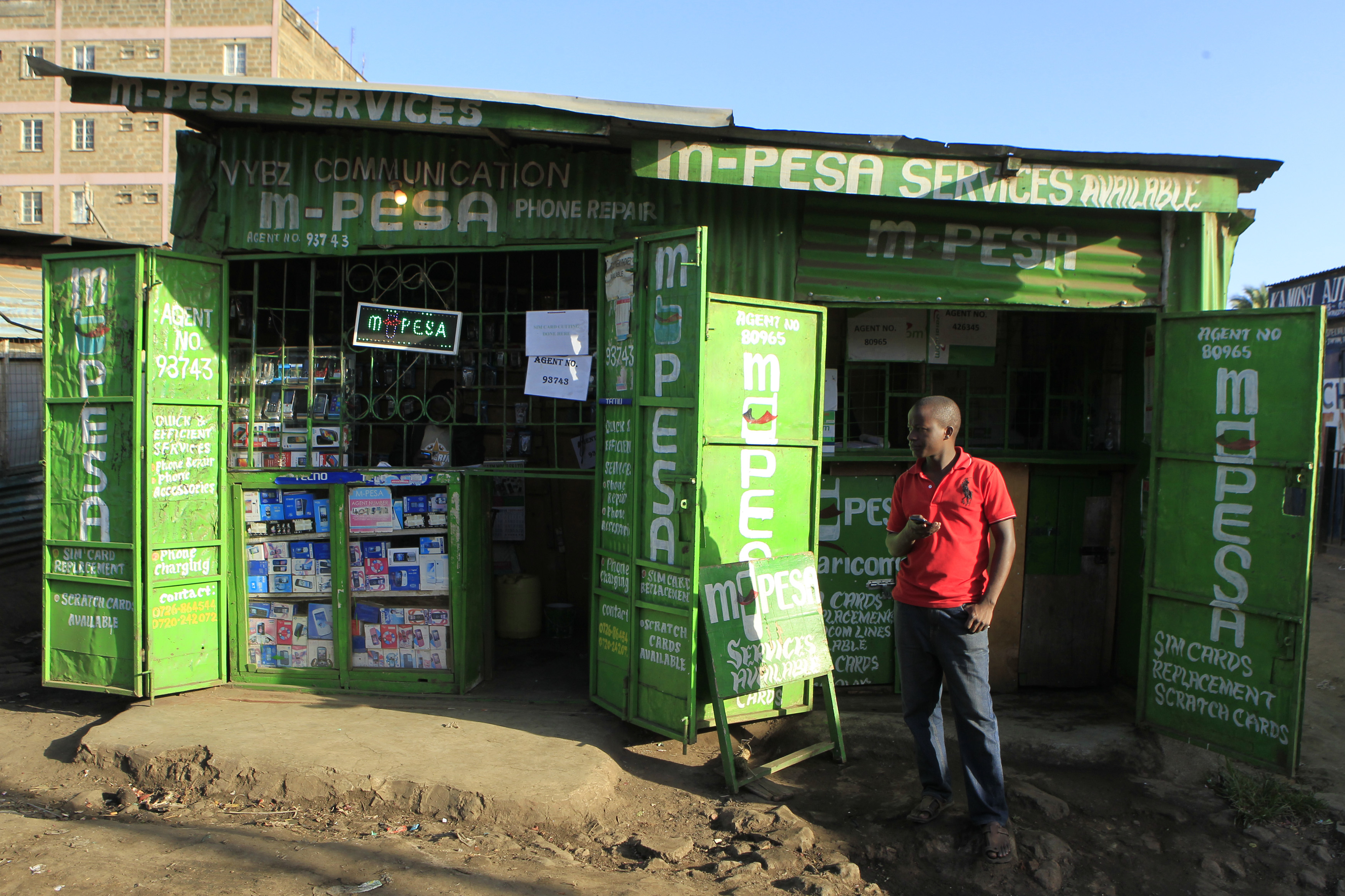 A man waits for M-Pesa customers at his shop in Kibera in Kenya's capital Nairobi December 31, 2014. Safaricom, Kenya's biggest telecoms firm, is a model of how technology can be used to financially include millions of people with mobile telephones but without access to traditional infrastructure such as the banks that are available to the wealthy or those living in cities. Safaricom in 2007 pioneered its M-Pesa mobile money transfer technology, now used across Africa, Asia and Europe. It proved that money can be made from people who earn a few dollars a day.  REUTERS/Noor Khamis (KENYA - Tags: BUSINESS SOCIETY SCIENCE TECHNOLOGY TELECOMS)