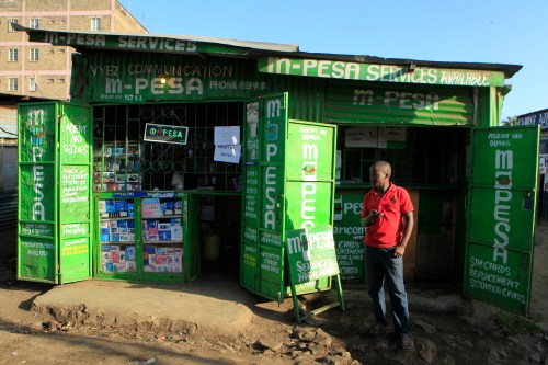 A man waits for M-Pesa customers at his shop in Kibera in Kenya's capital Nairobi December 31, 2014. Safaricom, Kenya's biggest telecoms firm, is a model of how technology can be used to financially include millions of people with mobile telephones but without access to traditional infrastructure such as the banks that are available to the wealthy or those living in cities. Safaricom in 2007 pioneered its M-Pesa mobile money transfer technology, now used across Africa, Asia and Europe. It proved that money can be made from people who earn a few dollars a day.  REUTERS/Noor Khamis (KENYA - Tags: BUSINESS SOCIETY SCIENCE TECHNOLOGY TELECOMS)
