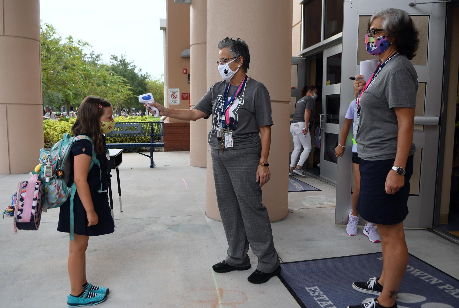 A school employee checks the temperature of a student as she returns to school on the first day of in-person classes in Orange County at Baldwin Park Elementary School on August 21, 2020 in Orlando, Florida, US. Face masks and temperature checks are required for all students as Florida's death toll from COVID-19 now exceeds 10,000, with some teachers refusing to return to their classrooms due to health concerns. (Photo by Paul Hennessy/NurPhoto)NO USE FRANCE