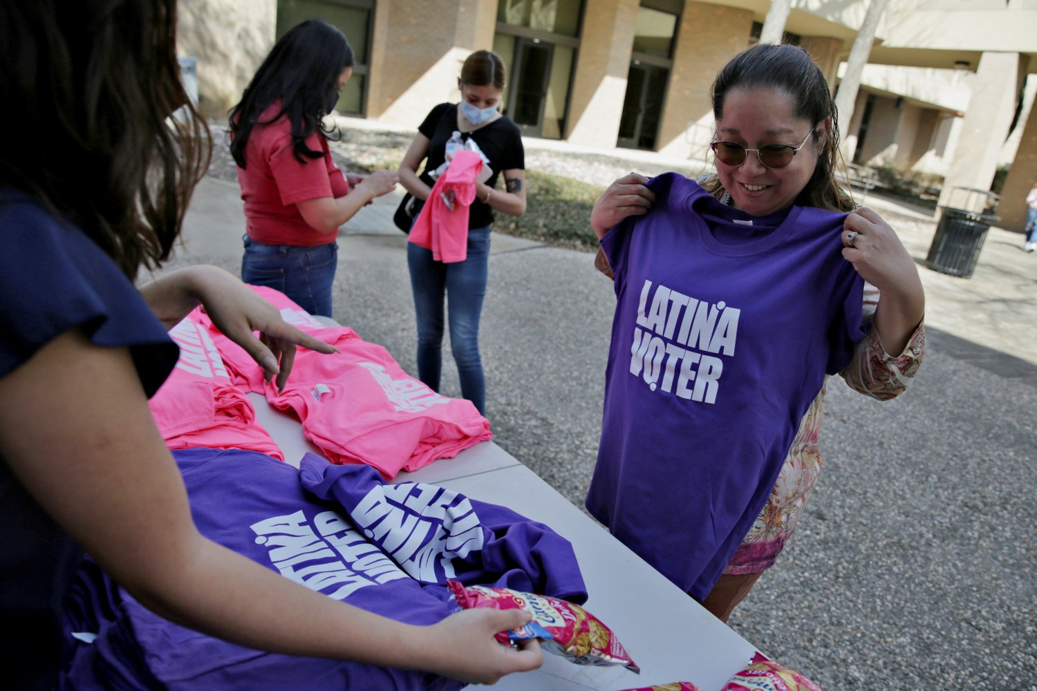 Naomi Martinez looks at a free shirt offered by Hey Chica!, a Latina leadership group empowering Latinas to vote, at the Dallas College Eastfield Campus in the primary election in Dallas, U.S., March 1, 2022.  REUTERS/Shelby Tauber