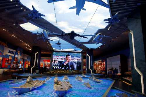 Models of military equipment and a giant screen displaying Chinese President Xi Jinping are seen at an exhibition at the Military Museum of the Chinese People's Revolution in Beijing, China October 8, 2022. REUTERS/Florence Lo