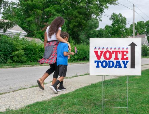 Multi Ethnic Mother and Son walking toward polling station to vote in election