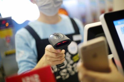 --FILE--A Chinese cashier scans the QR code through mobile payment service Alipay of Alibaba Group on the smartphone of a customer in a store in Shanghai, China, 11 December 2016. Increasingly popular smartphone, further implementation of "Internet +" program and continuous technological innovation have fueled the rapid growth of the Chinese mobile payment market with transaction volume for 2015 surging by 322.2% to RMB130.18 trillion and expected to maintain an AAGR of 142% over the next couple years to hit RMB13,776.5 trillion in 2020. With regard to third-party mobile payment, the transaction volume in China reported RMB21.96 trillion in 2015, an upsurge of 167% from a year ago, 90% of the market seized by Alipay and WeChat Pay. Supported by business data, third-party payment companies will continue to expand service functions, finally forming a development pattern of O2O (Online to Offline) services. In addition, driven by mobile-payment interest chain and against the background of tighter access to payment, the mobile payment market has undergone an expedited reshuffle and mobile phone vendors and traditional enterprises have stepped up their presence in 2016, further intensifying market competition. Technologically, as two-dimensional barcode (or QR code) is permitted, 2D barcode payment technology will keep having an edge. Meanwhile, with higher requirements on payment security, other technologies like NFC, HCE, Token and biological recognition will mature gradually.No Use China. No Use France.