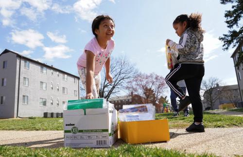 With schools closed due to coronavirus, a girl reaches for a bag of school supplies delivered by volunteers in a low income neighbourhood of Falls Church, Virginia, U.S., March 17, 2020.  REUTERS/Kevin Lamarque