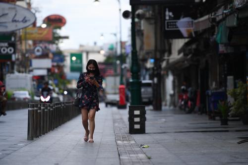 A woman wearing a face mask uses on her mobile phone while walking along the street at Khao San Road during lockdown due to COVID-19 pandemic in Thailand on August 28, 2021 in Bangkok, Thailand. (Photo by Vachira Vachira/NurPhoto)NO USE FRANCE