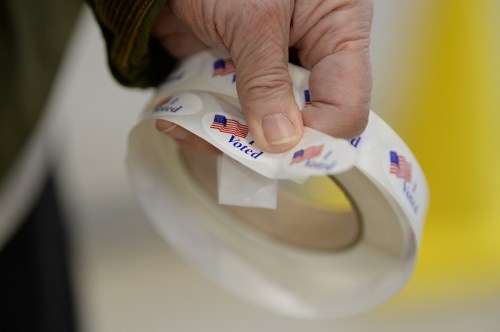 A poll worker waits to hand out stickers as Americans cast their votes during the midterm elections at Eastport Elementary School in Annapolis, U.S., November 8, 2022.      REUTERS/Mary F. Calvert