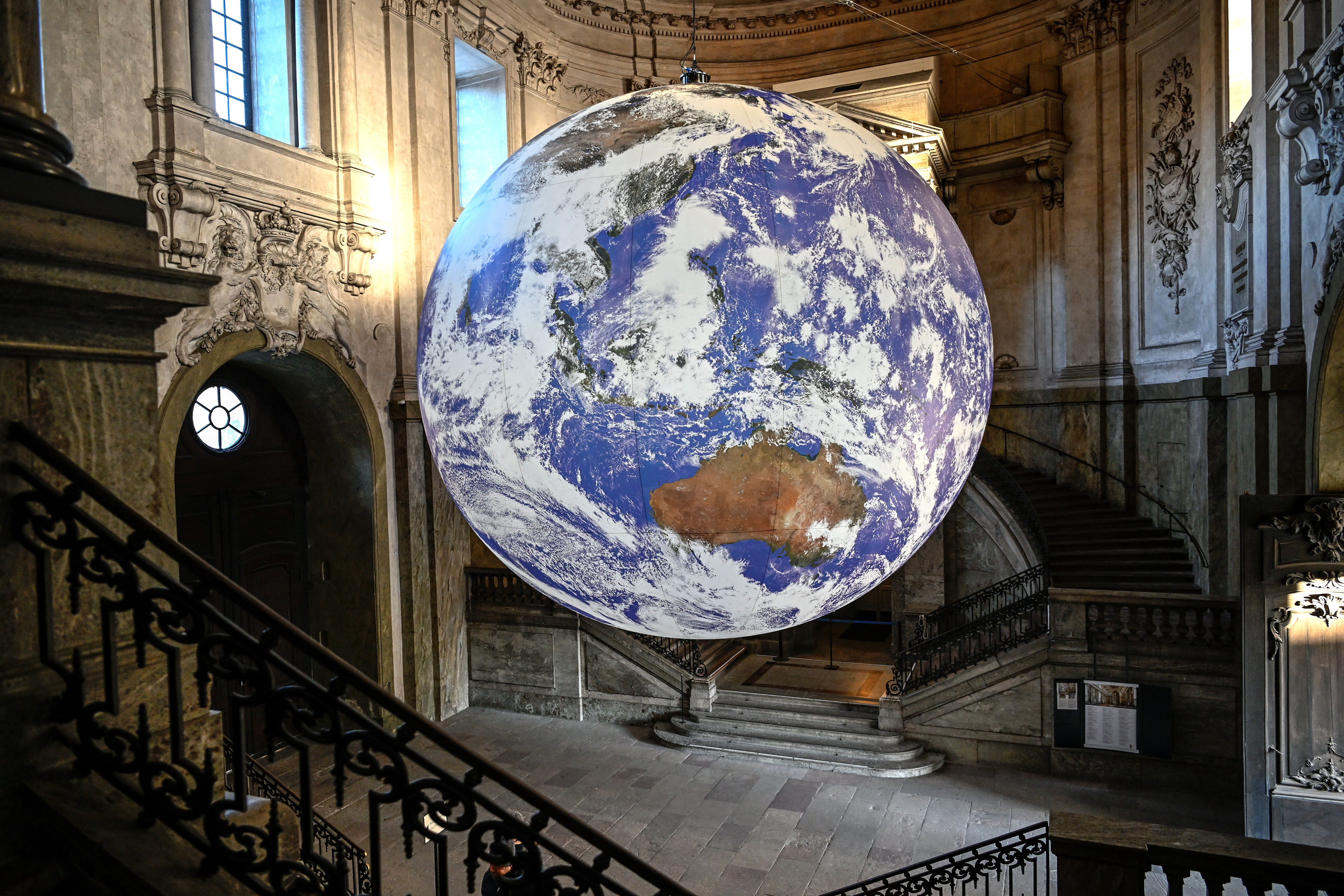 Visitors look at the artwork Gaia, created by artist Luke Jerram, which hangs in the Royal Palace's south vault in Stockholm, Sweden Decemer 8, 2022. Gaia is a globe measuring seven meters in diameter, created from images taken from NASA photographs of the Earth's surface. It is one of 22 works of art that illuminate Stockholm during the "Nobel Week Lights" festival. TT News Agency/Anders Wiklund via REUTERS      ATTENTION EDITORS - THIS IMAGE WAS PROVIDED BY A THIRD PARTY. SWEDEN OUT. NO COMMERCIAL OR EDITORIAL SALES IN SWEDEN.