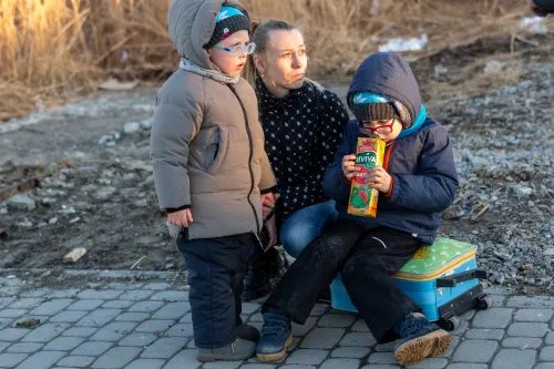 Ukrainian family waits for their relative after crossing into Poland