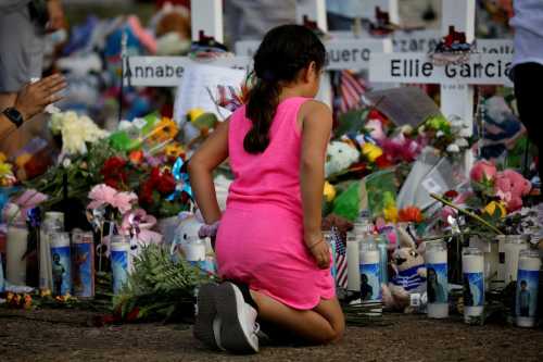 A girl pays respects at the memorial at Robb Elementary school, where a gunman killed 19 children and two adults, in Uvalde, Texas, U.S. May 28, 2022. REUTERS/Marco Bello