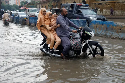 A man and students ride on a motorcycle on a flooded road, following rains during the monsoon season in Karachi, Pakistan August 10, 2022. REUTERS/Akhtar Soomro     TPX IMAGES OF THE DAY