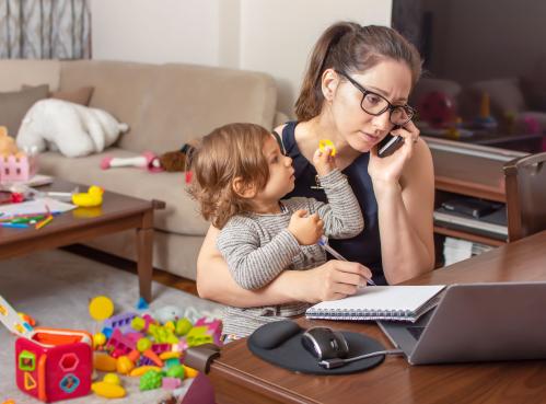 A mother holds her baby while on the phone