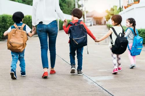 Students walk toward their community school with their caregiver.