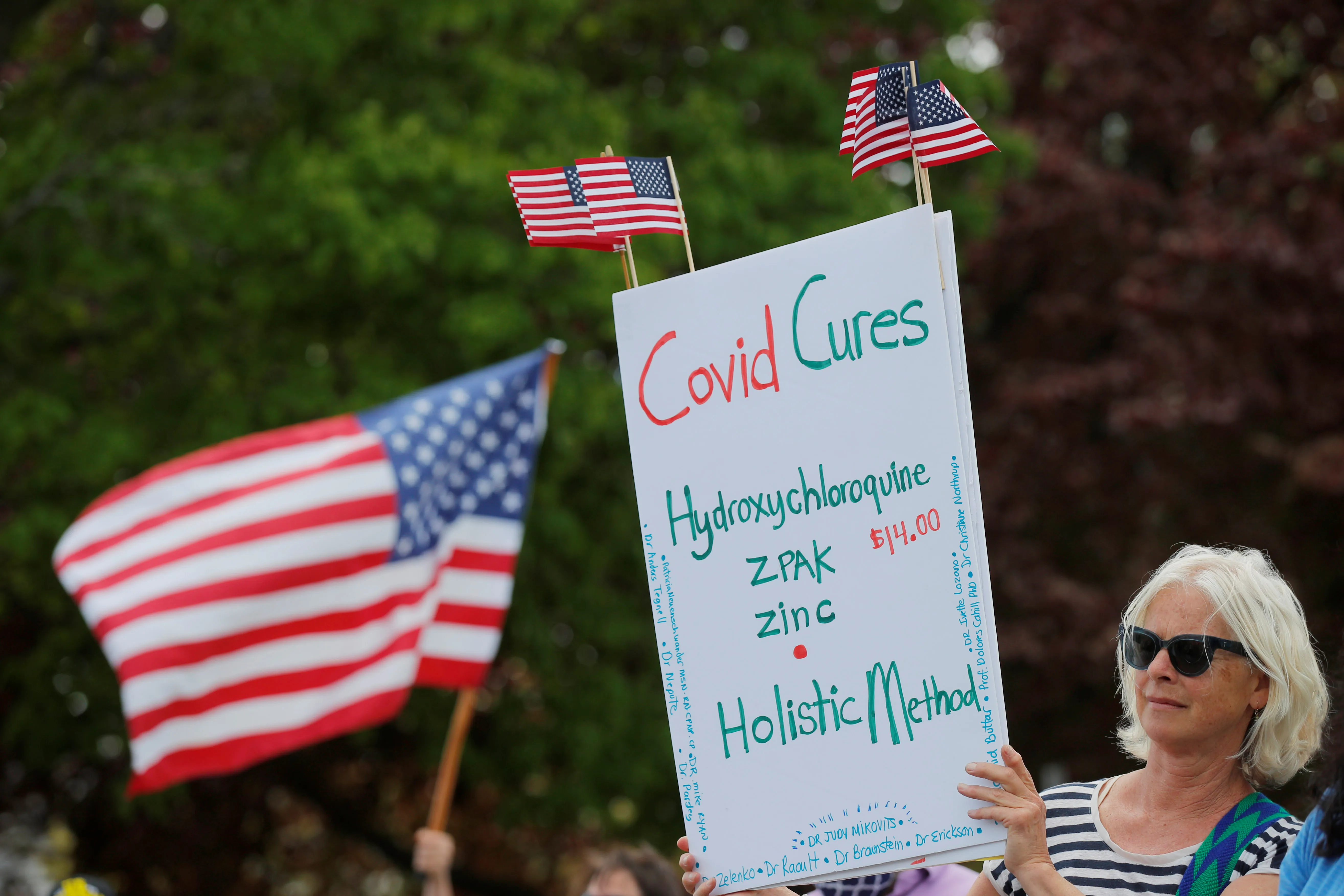 A woman holds a sign listing "Covid Cures," including hydroxychloroquine, at a protest against restrictions implemented in response to the coronavirus disease (COVID-19) outbreak near Massachusetts Governor Charlie Baker’s house in Swampscott, Massachusetts, U.S., May 16, 2020.   REUTERS/Brian Snyder