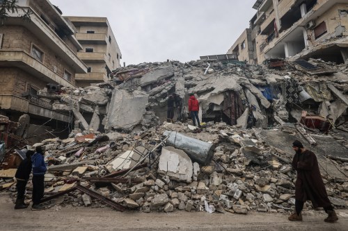 Syrian civilians inspect a destroyed residential building after the magnitude 7.8 earthquake that hit northern Syria.