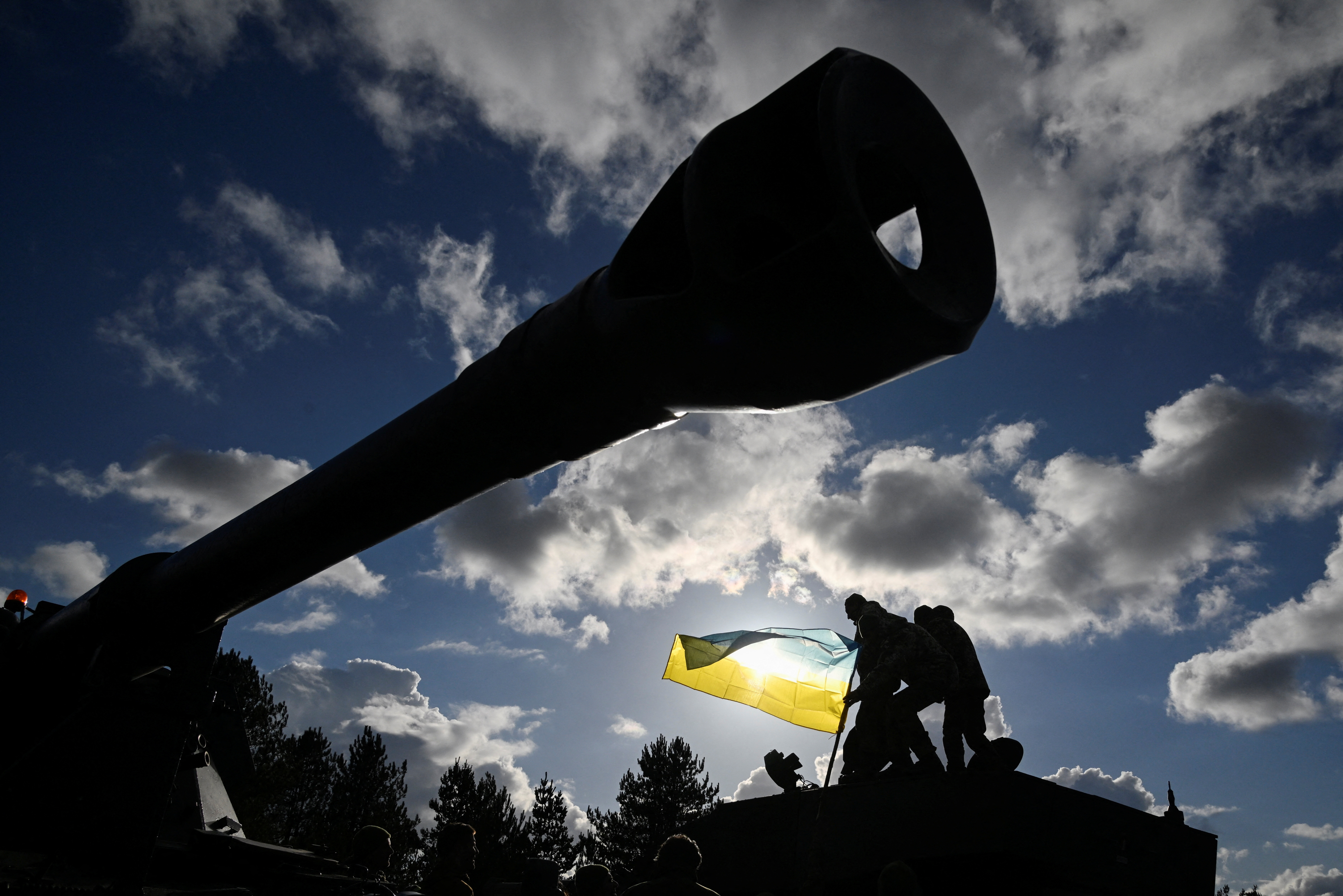 Ukrainian personnel hold a Ukrainian flag as they stand on a Challenger 2 tank during training at Bovington Camp, near Wool in southwestern Britain, February 22, 2023. REUTERS/Toby Melville