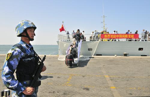 A navy soldier (L) of People's Liberation Army (PLA) stands guard as Chinese citizens board the naval ship "Linyi" at a port in Aden, March 29, 2015. China's Defence Ministry said on Tuesday its warships had completed an evacuation of Chinese nationals from Yemen, with more than 570 people safely transported across the Red Sea to Djibouti to be flown home. The Chinese characters on the banner read, welcome Chinese compatriots on board. Picture taken March 29, 2015. REUTERS/Stringer  CHINA OUT. NO COMMERCIAL OR EDITORIAL SALES IN CHINA