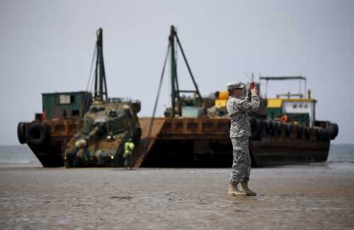 A U.S. Marine takes photographs as a South Korean army's K-55 self-propelled artillery vehicle gets out of a barge during the Combined Joint Logistics Over The Shore (CJLOTS) exercise, at a seashore in Taean, South Korea, July 6, 2015.  REUTERS/Kim Hong-Ji
