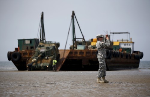 A U.S. Marine takes photographs as a South Korean army's K-55 self-propelled artillery vehicle gets out of a barge during the Combined Joint Logistics Over The Shore (CJLOTS) exercise, at a seashore in Taean, South Korea, July 6, 2015.  REUTERS/Kim Hong-Ji