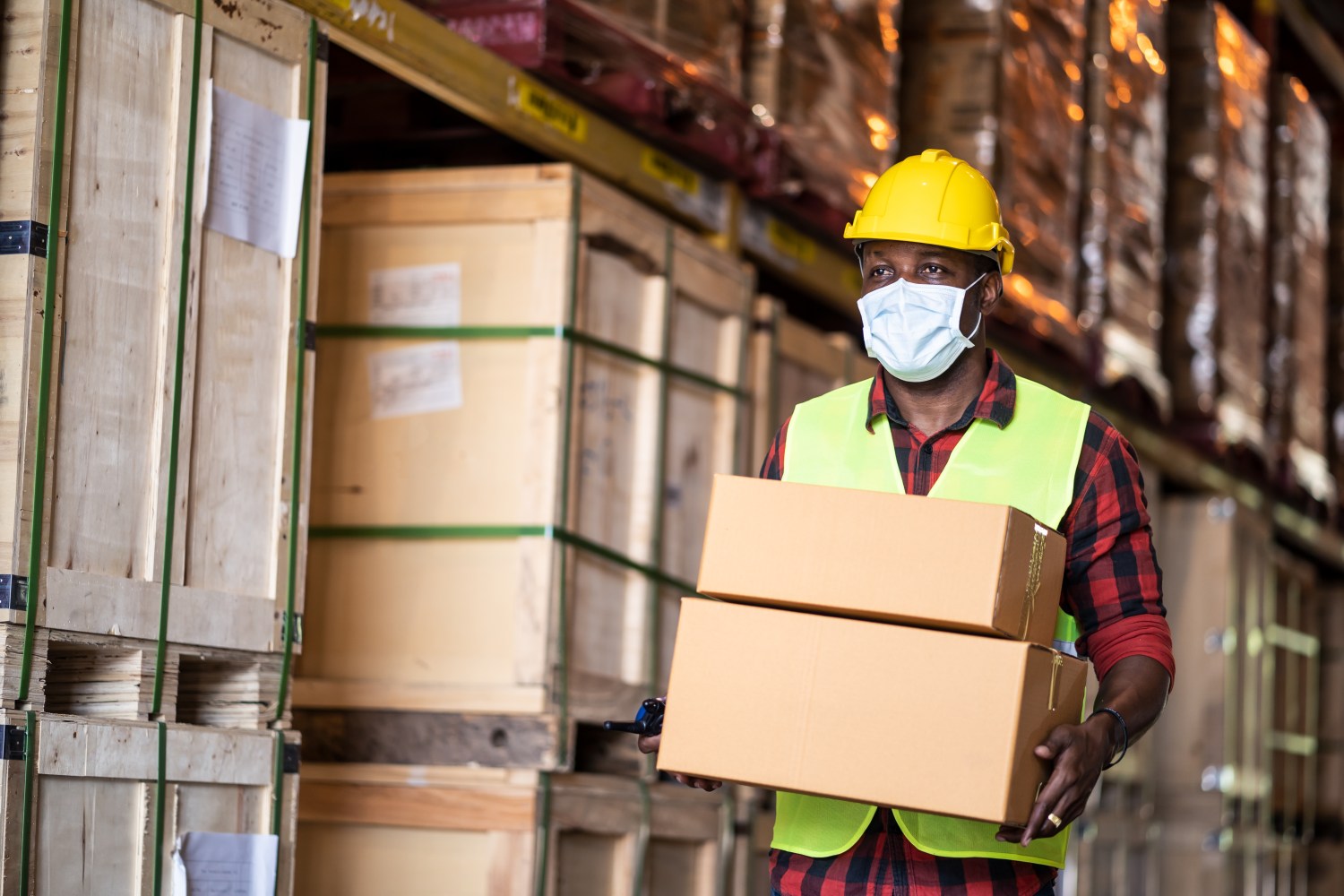 image of a black male warehouse worker carrying boxes.