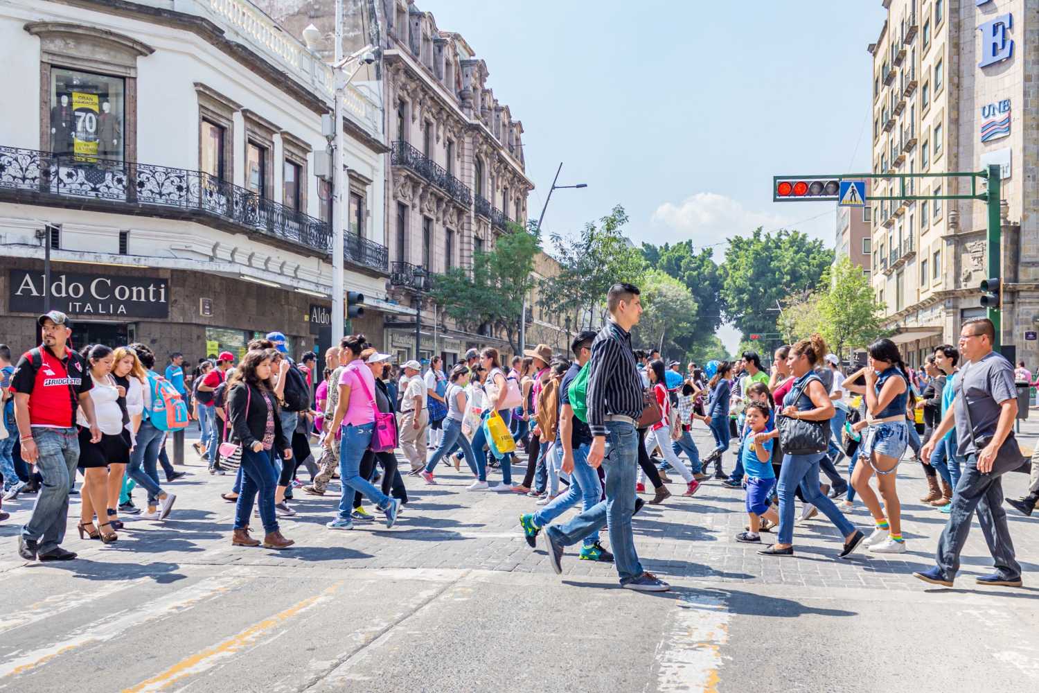 Guadalajara, Jalisco Mexico. February 11, 2017. Crowd of people crossing the street at corner against traffic light with red lights