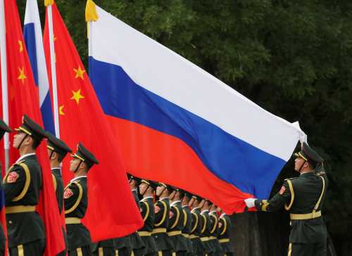A military officer adjusts a Russian flag ahead of a welcome ceremony hosted by Chinese President Xi Jinping for Russian President Vladimir Putin outside the Great Hall of the People in Beijing, China June 8, 2018. REUTERS/Jason Lee