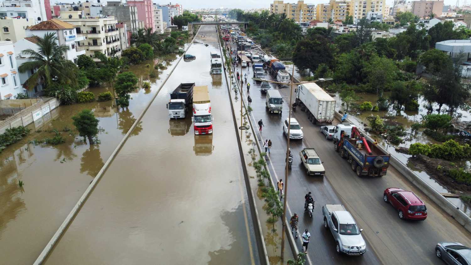 An aerial view shows residents making their way through a flooded street after torrential rain caused intense flooding in Dakar, Senegal August 6, 2022. REUTERS/Ngouda Dione