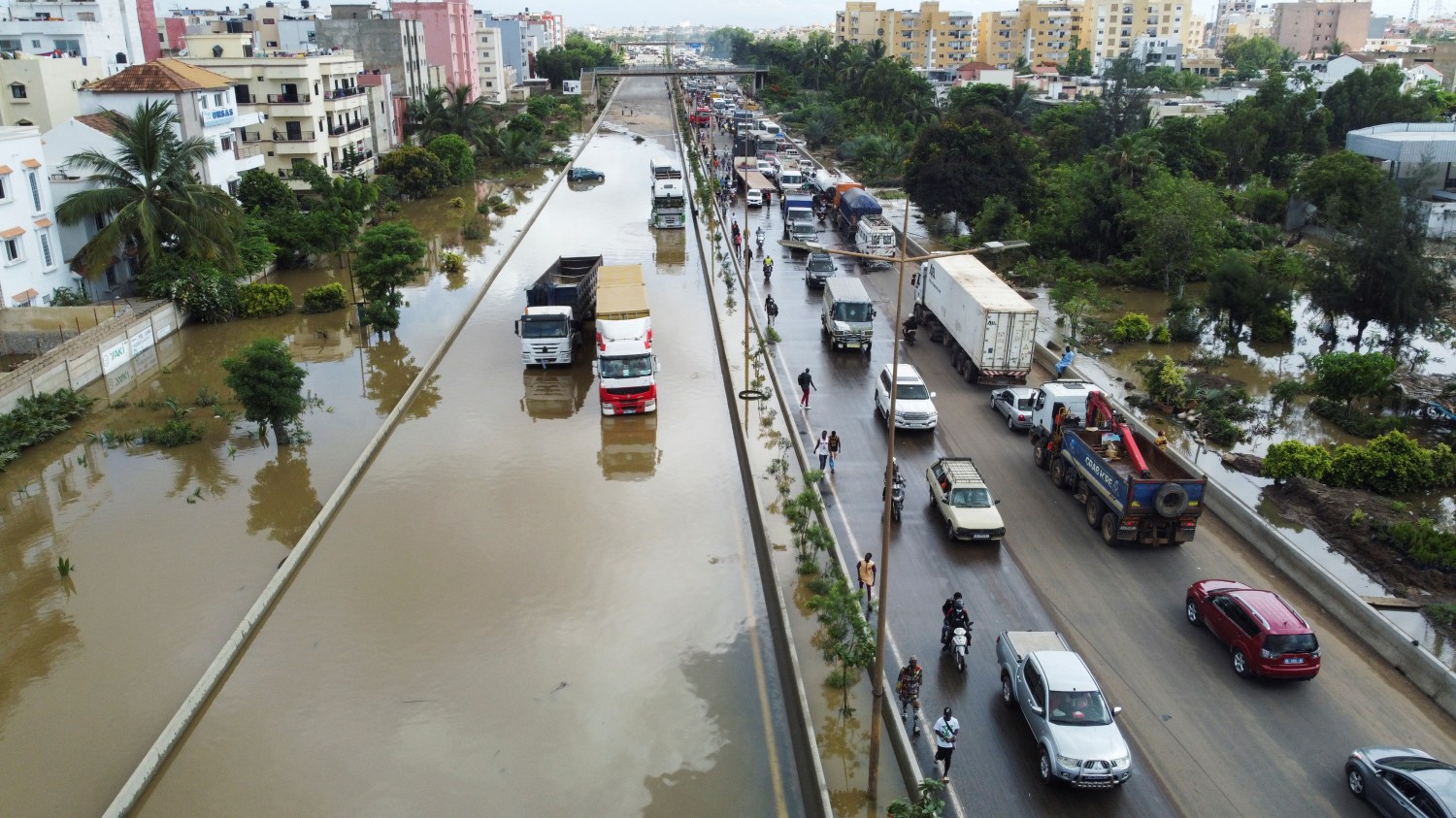 An aerial view shows residents making their way through a flooded street after torrential rain caused intense flooding in Dakar, Senegal August 6, 2022. REUTERS/Ngouda Dione