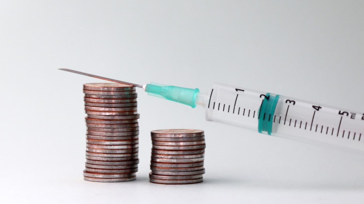 Stack of coins and a hypodermic needle.