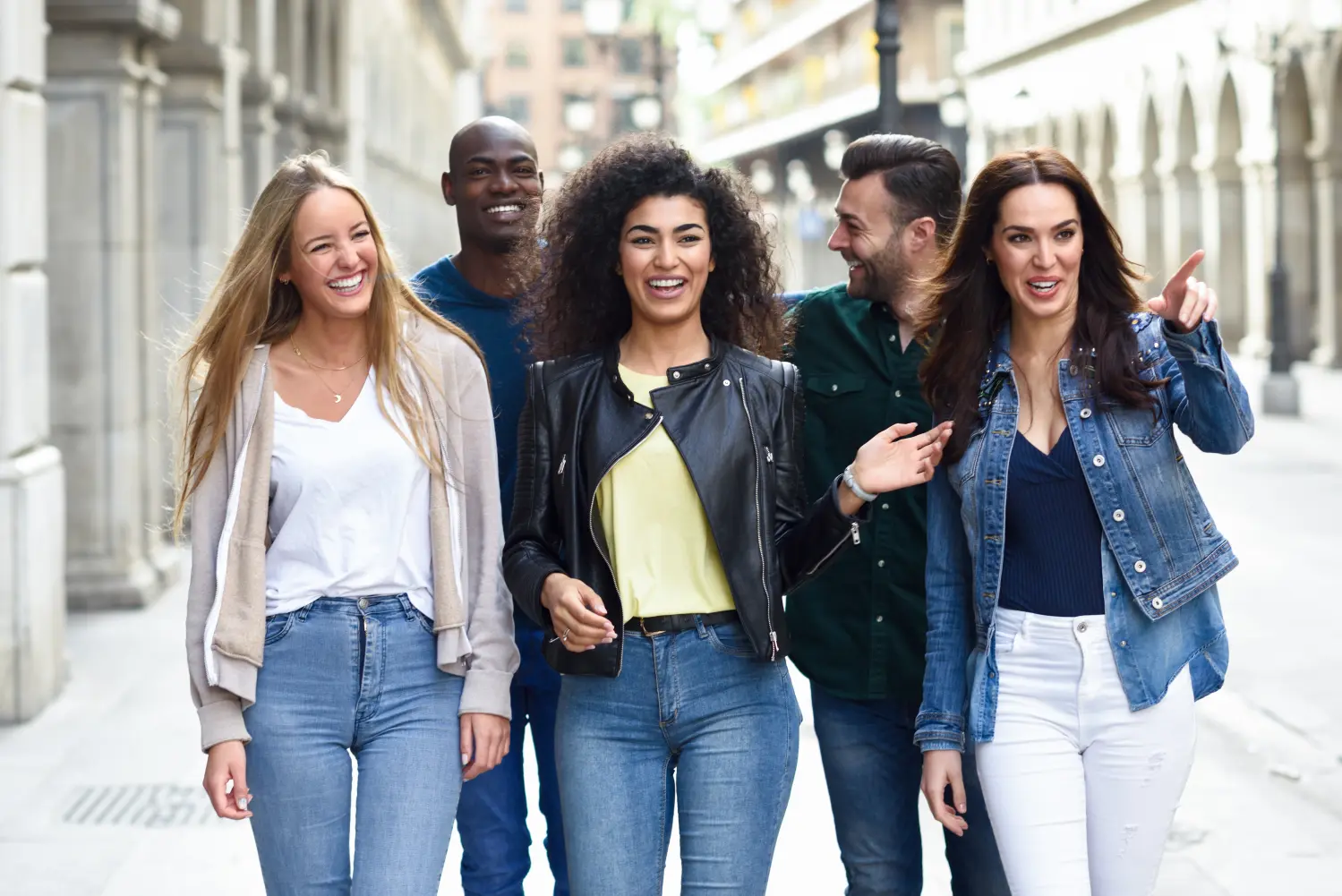 Multi-ethnic group of young people having fun together outdoors in urban background. group of people walking together